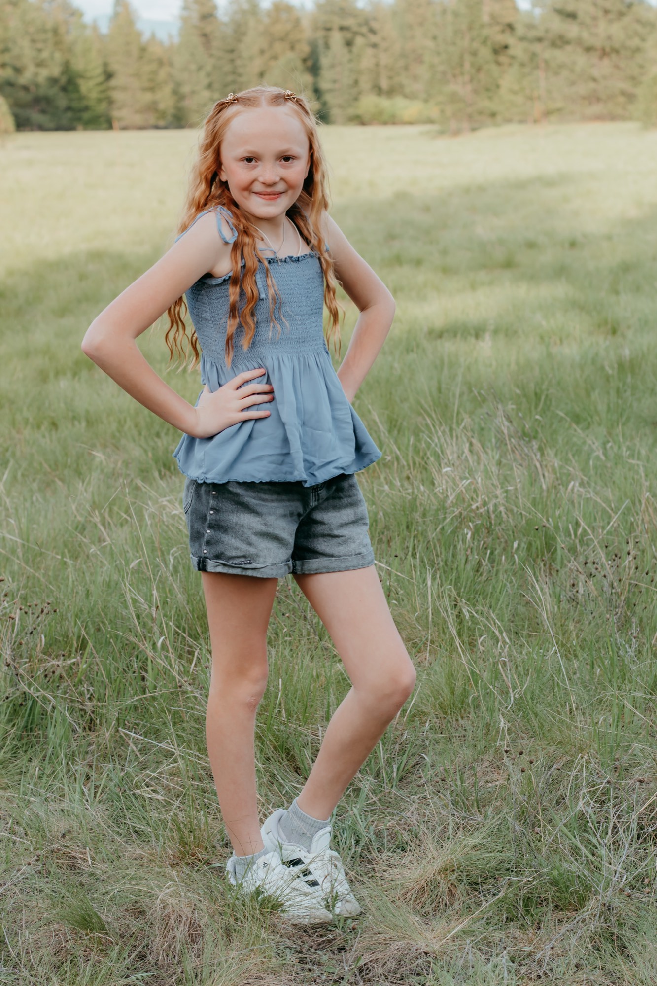 Young girl smiling in a green meadow during a children's photo session in North Idaho