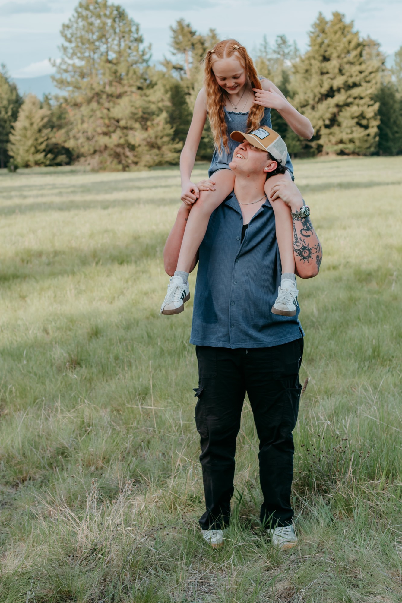 Dad lifting daughter on his shoulders in a North Idaho meadow, both laughing during a family photo session