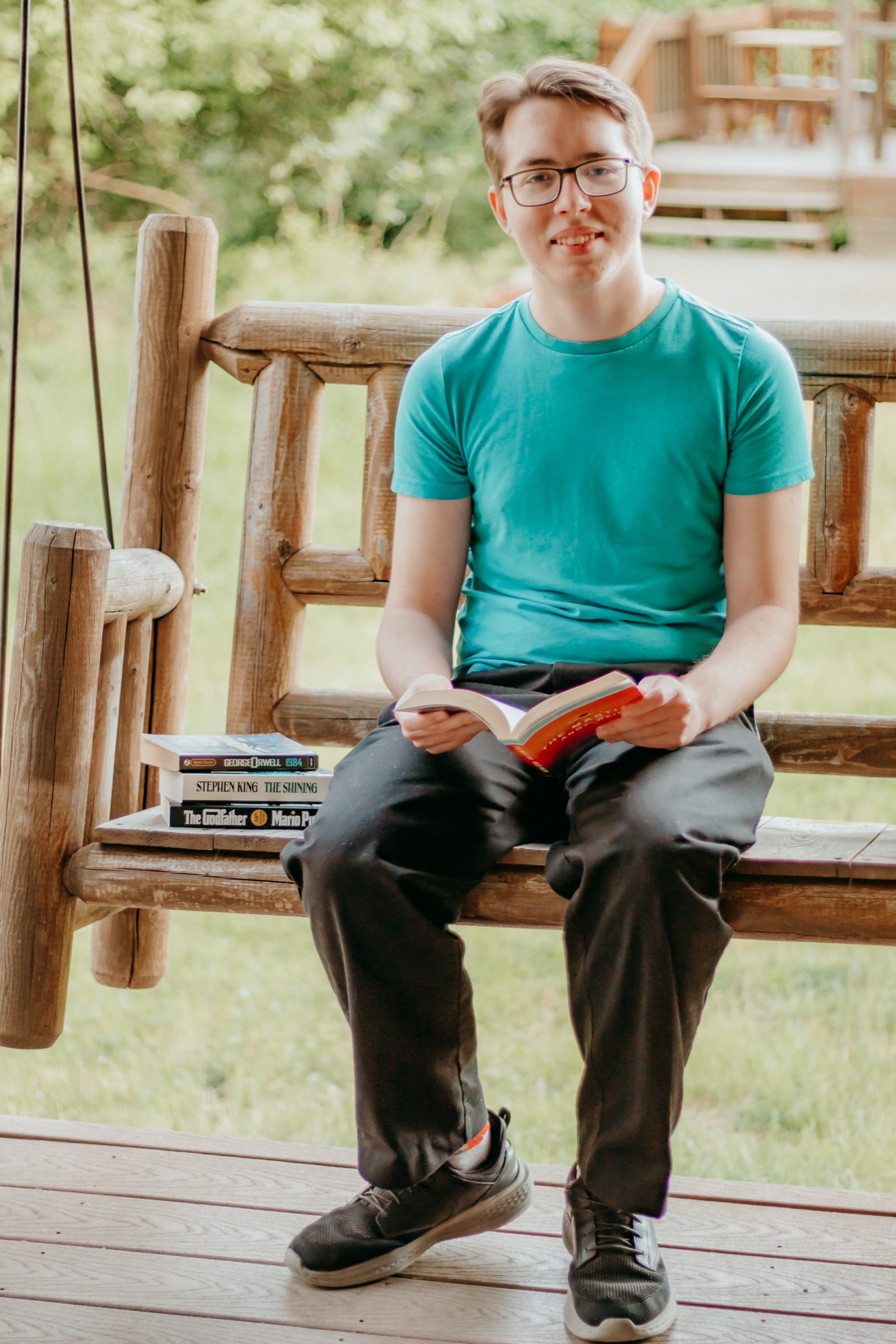 Senior pictures North Idaho on a log porch swing with books